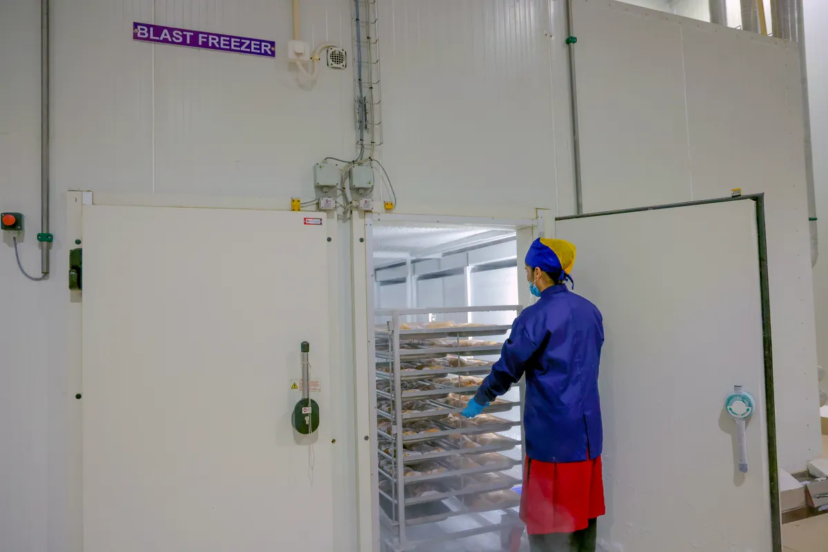 Worker wheeling a rack into the blast freezer at Rudrapur